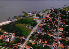 A fotografia mostra uma vista panorâmica e de cima da cidade de São Caetano de Odivelas. É possível ver o desenho de ruas, casas, vegetação e, na parte superior, parte da orla da cidade. Está de dia.